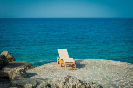 Sunbed on the rocks next to seaの写真素材