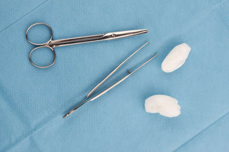 Medical scissors, tweezers and swabs close up on blue backgroundの写真素材
