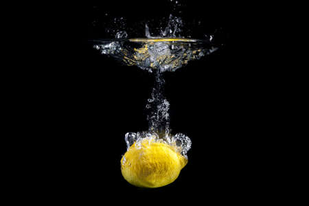 Fresh fruit dropped into water with splash on black background の写真素材