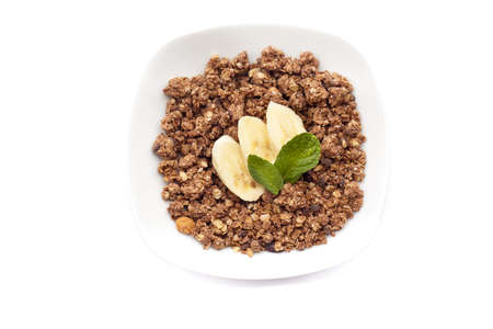 Delicious and healthy muesli in bowl with banana and mint on white backgroundの写真素材