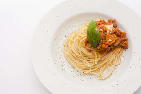 portion of spaghetti bolognese on a white plate, close-up
