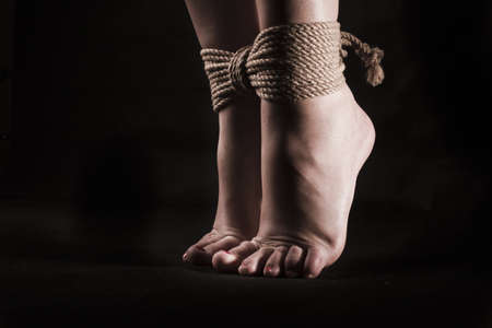 detail suspended bound feet submissive young girl on a black background / BDSM themeの写真素材