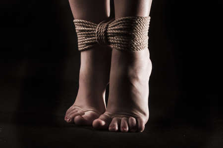 detail suspended bound feet submissive young girl on a black background / BDSM themeの写真素材