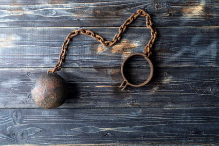Metal ball with chain on the leg. Prison equipment.