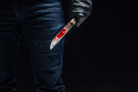 Serial killer's hand with bloody knife and black glovesの写真素材