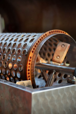 Industrial grape destemming machine showing perforated metal cylinder used in wine production. The mechanical equipment features holes for separating grapes from stems during harvest processing.の写真素材
