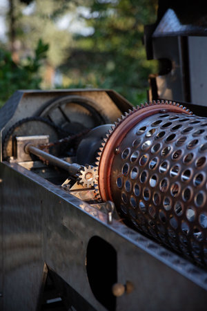 Close-up of wine press crusher gears and mechanical components. The metal gears and perforated cylinder are part of the grape crushing and pressing machinery used during harvest.の写真素材