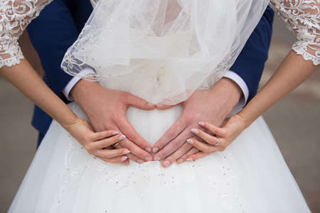 Wedding: bride and groom holding their hands in a heart shapeの写真素材