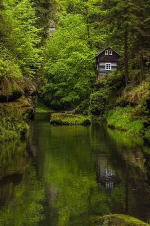 Beautiful hut among the trees reflecting in the river Kamenice, National Park Bohemian Switzerland (Ceske Svycarsko), Czech Republicの写真素材