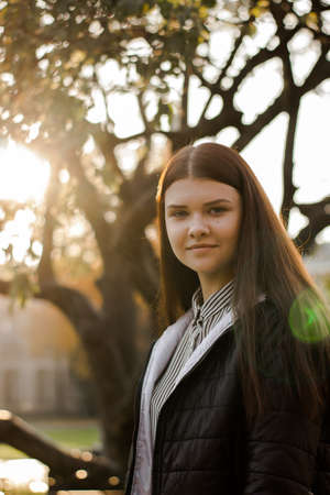 Portrait of a young beautiful brown-haired girl. A young lady with a confident smile looks straight