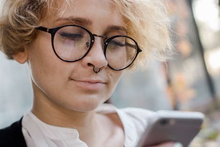 Close up of a smiling young girl looking at the phone is standing near a stained glass window. Woman...