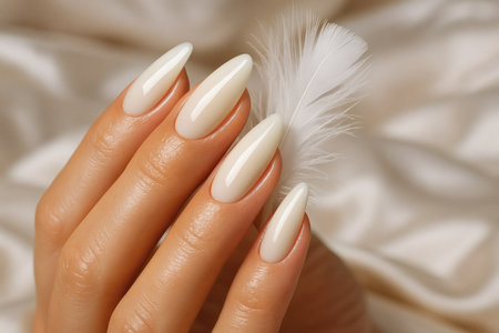 Female hand with white manicure and feather on the background of fabricの素材