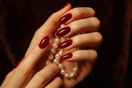 Beautiful female hands with red manicure and white pearlsの素材