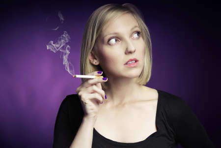 Young woman smoking cigarette  Purple background 
