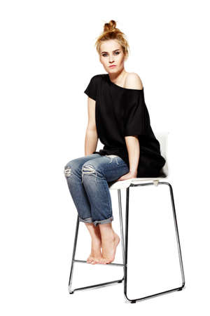 Portrait of a young woman sitting on modern chair. Isolated on white background.