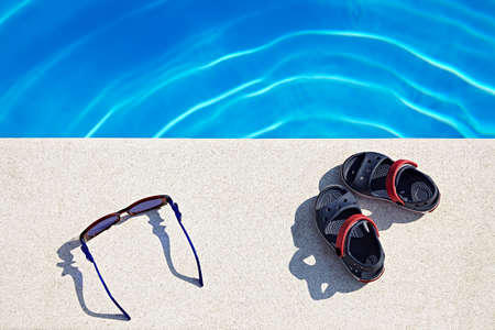 Sunglasses and sandals at the swimming pool at sunny day. Copy space.の写真素材