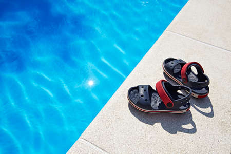 Pair of baby sandals at the swimming pool at sunny day. Copy space.の写真素材