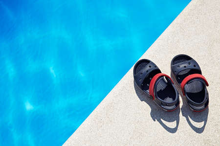 Pair of baby sandals at the swimming pool at sunny day. Copy space.の写真素材