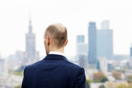 Businessman standing on the roof and looking at downtownの写真素材