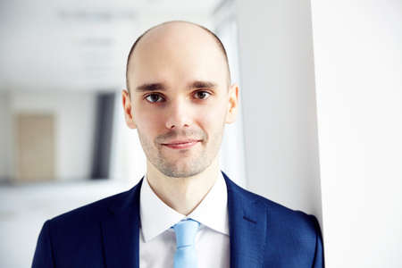 Portrait of calm young businessman in the office. Light background. Close up.