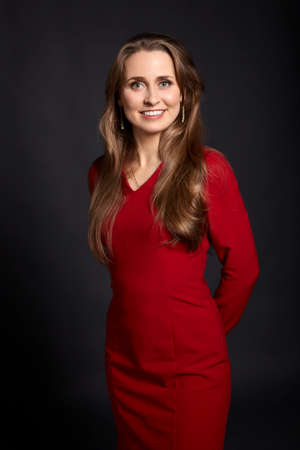 Studio portrait of young attractive woman with long blonde hair, white smile and green eyes on black background.の写真素材