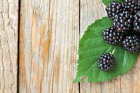 Juicy Blackberries with leaves on rustic wooden background. Top viewの写真素材