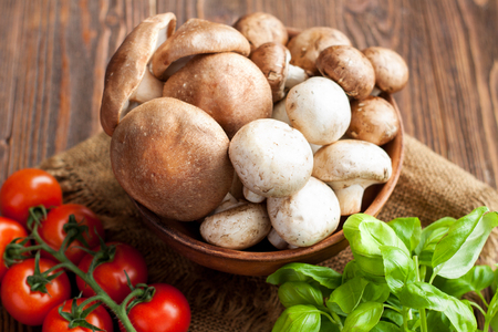 Fresh mushrooms, cherry tomatoes and basil on wooden backgroundの写真素材