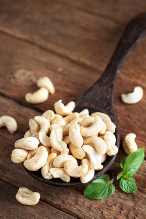Cashew in wooden spoon on rustic tableの写真素材