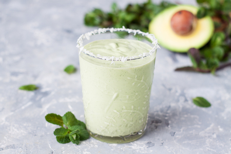 Healthy green milkshake or smoothie with avocado and mint on grey stone tableの写真素材