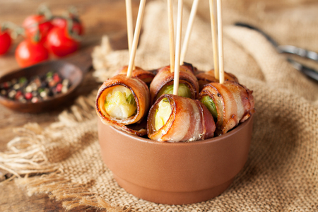 Bacon wrapped brussels sprouts served with cherry tomatoes in ceramic bowl. Appetizer rollsの写真素材