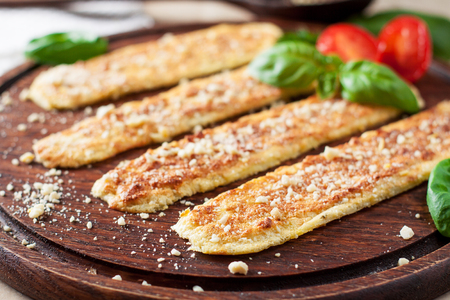 Vegan breadsticks with garlic and cashew cheese served with tomatoes and basil on wooden cutting boardの写真素材