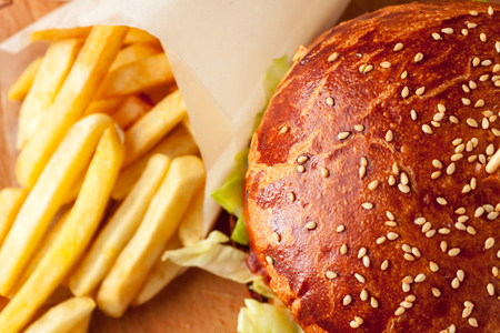 Craft beef burger and french fries on wooden cutting board