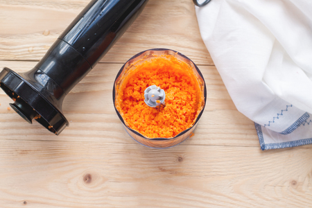 Grating peeled carrots in food processor. Preparation of gluten free pumpkin and carrot muffinsの写真素材