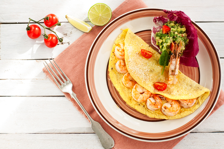 Omelette with shrimps, cheese and avocado and shrimp salsa served with cherry tomatoesの写真素材