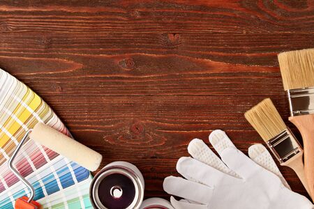 Diverse painting tools, brushes, can with paint, color guide palette on wooden table with place for...