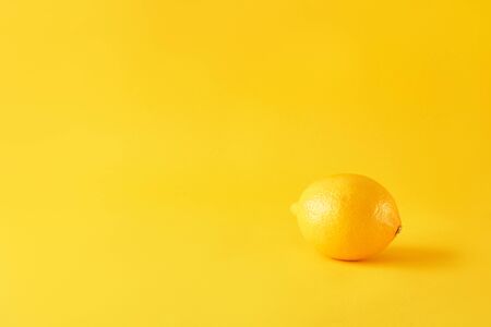 Ripe lemon on yellow paper. Juicy summer vitamin and diet concept. Minimalism, monochrome, with space for text.の写真素材