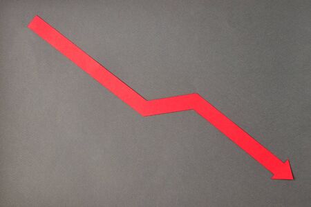 Crisis composition with red down arrow on grey paper background. Flat lay top view, minimal style with copy space.の写真素材