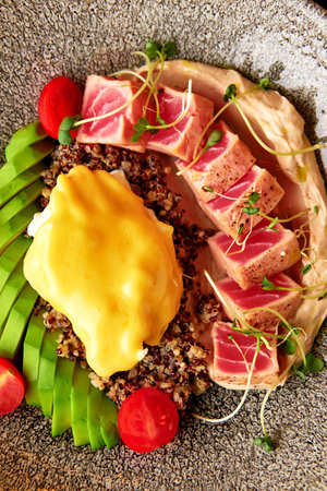 Quinoa with seared tuna and poached egg, served with hummus, fresh avocado and tomato. Healthy...