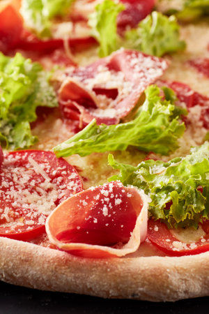 Freshly baked pizza with prosciutto, lettuce salad and parmesan.の写真素材