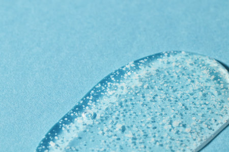 Smoothing scrub wash gel drop on blue background. Clear liquid gel with polishing beads for gentle exfoliation swatch closeup.の写真素材