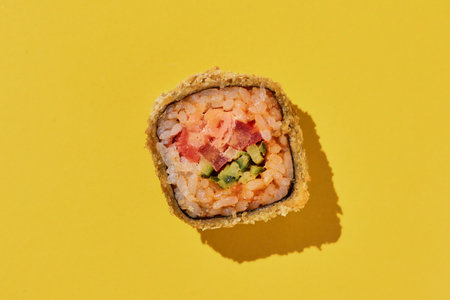 Fresh hot sushi roll with shrimp, pepper and cucumber in panko on yellow background, top view.の写真素材