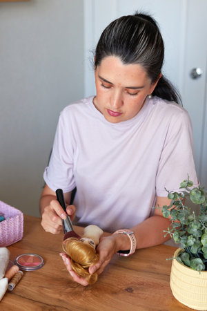 Portrait of creative young adult woman making handmade doll, painting doll face.の写真素材