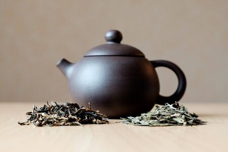 Small ceramic teapot and two heaps of teaの写真素材