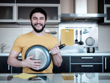 Funny cooking. Adult man in the kitchen with dripping pot like guitarの写真素材