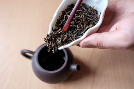 Filling a brown teapot through a funnelの写真素材