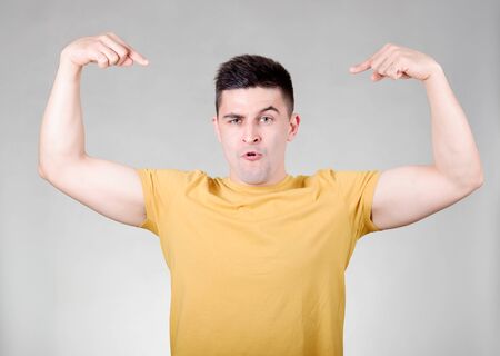 Handsome smiling man pointing to themselves isolated over gray backgroundの写真素材