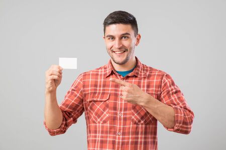 Young man holding and showing blank business card isolated on gray backgroundの写真素材