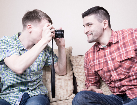 Two funny guys shooting portrait sitting on couchの写真素材