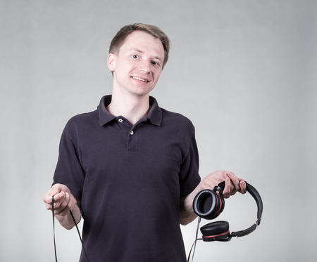 Young hansome man listening music with headphones on grey backgroundの写真素材