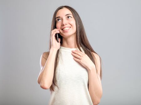 Beautiful smiling woman talking on phone isolated on gray background